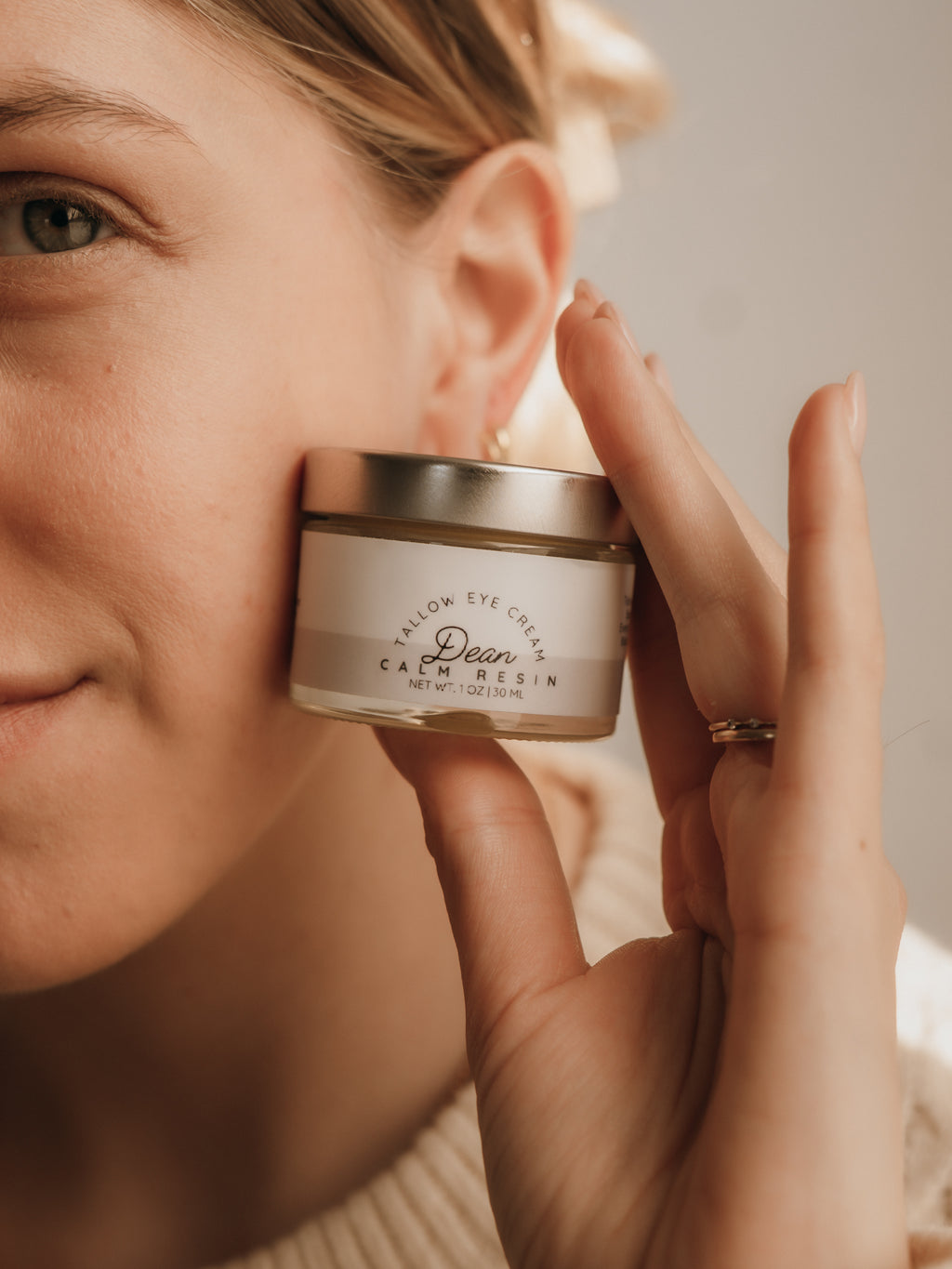 Person holding a skincare product close to their face