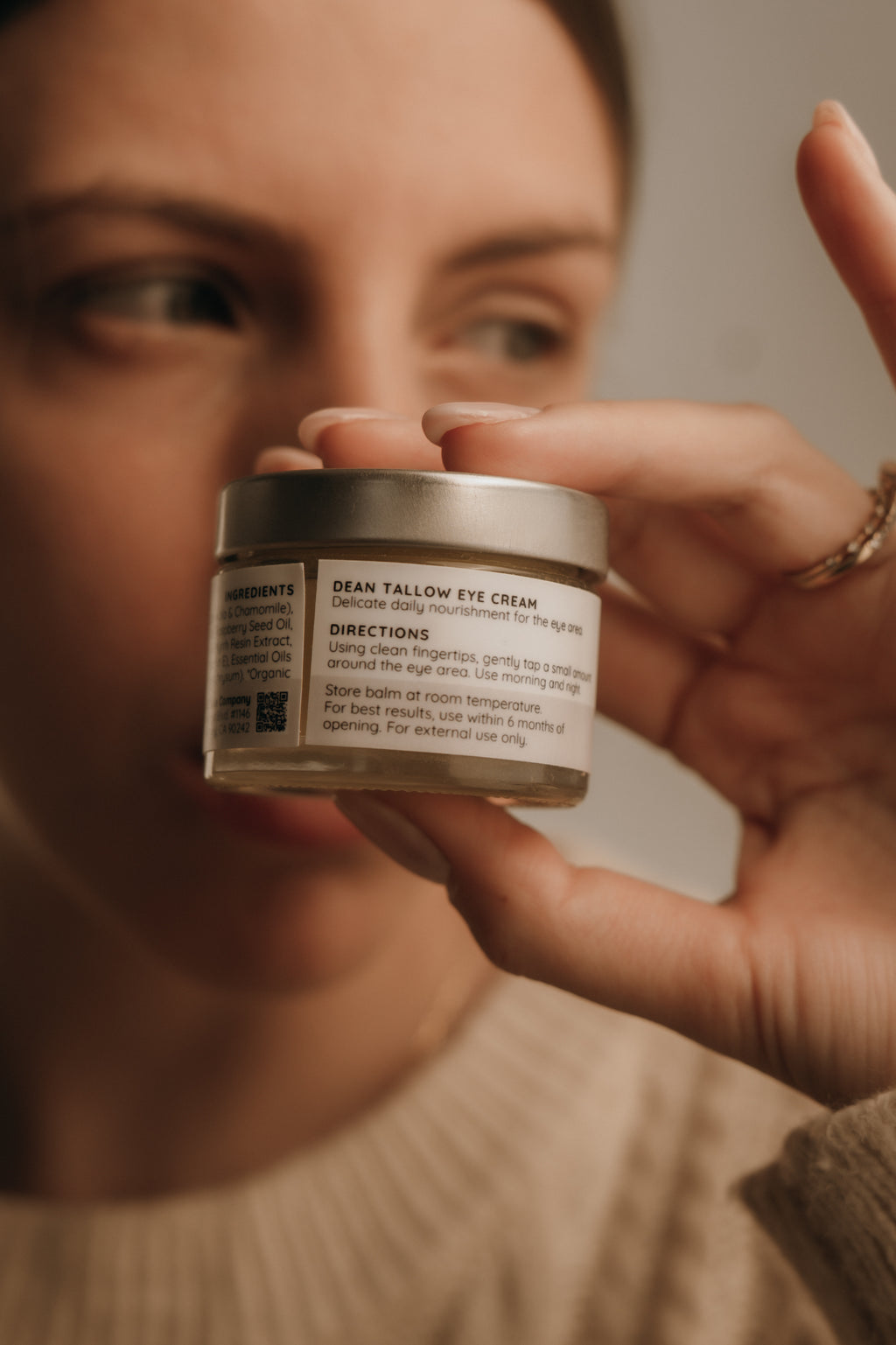 Person holding a jar of eye cream with a blurred background