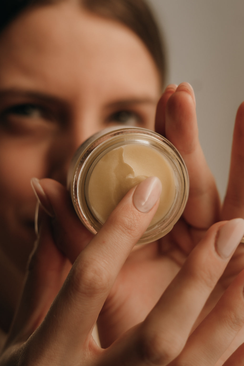 Person holding a jar of cream close to their face