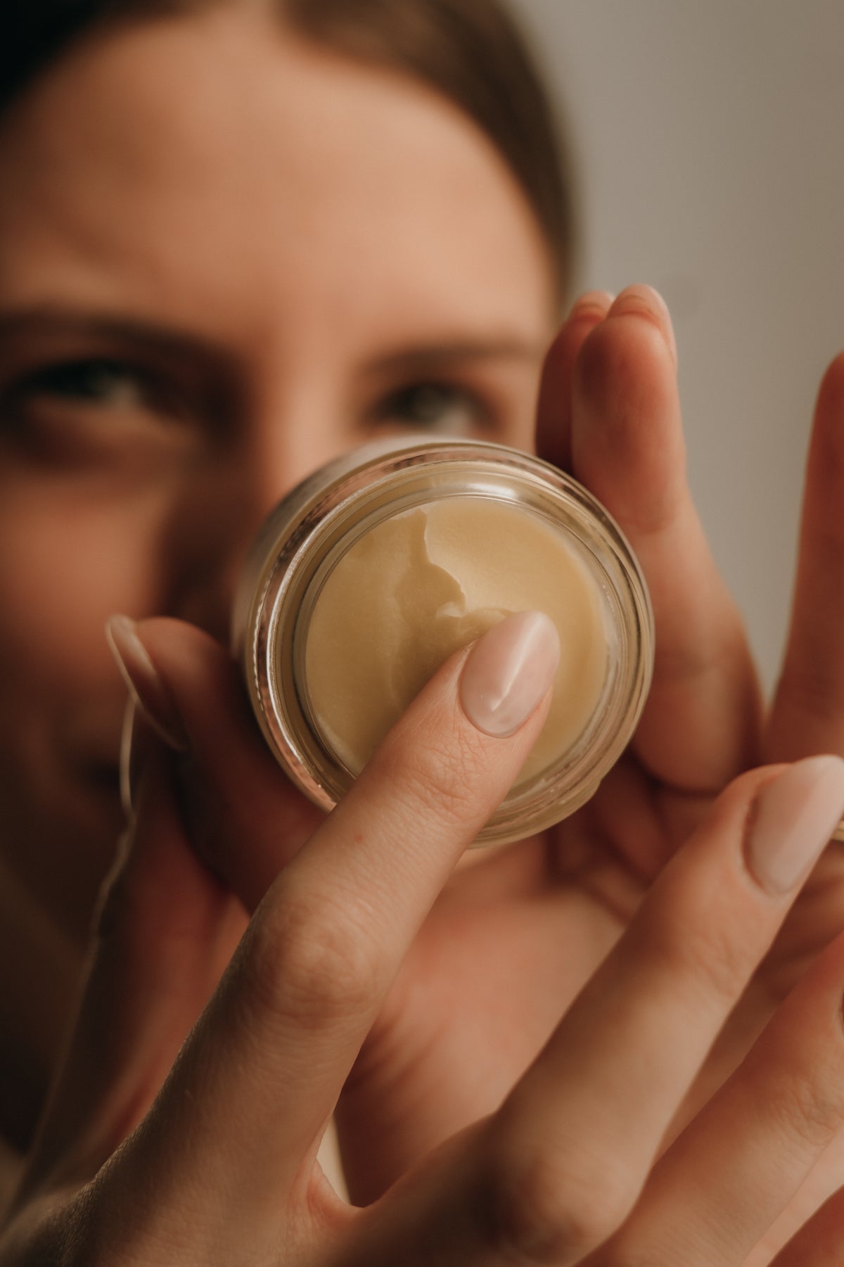 Person holding a jar of cream close to their face