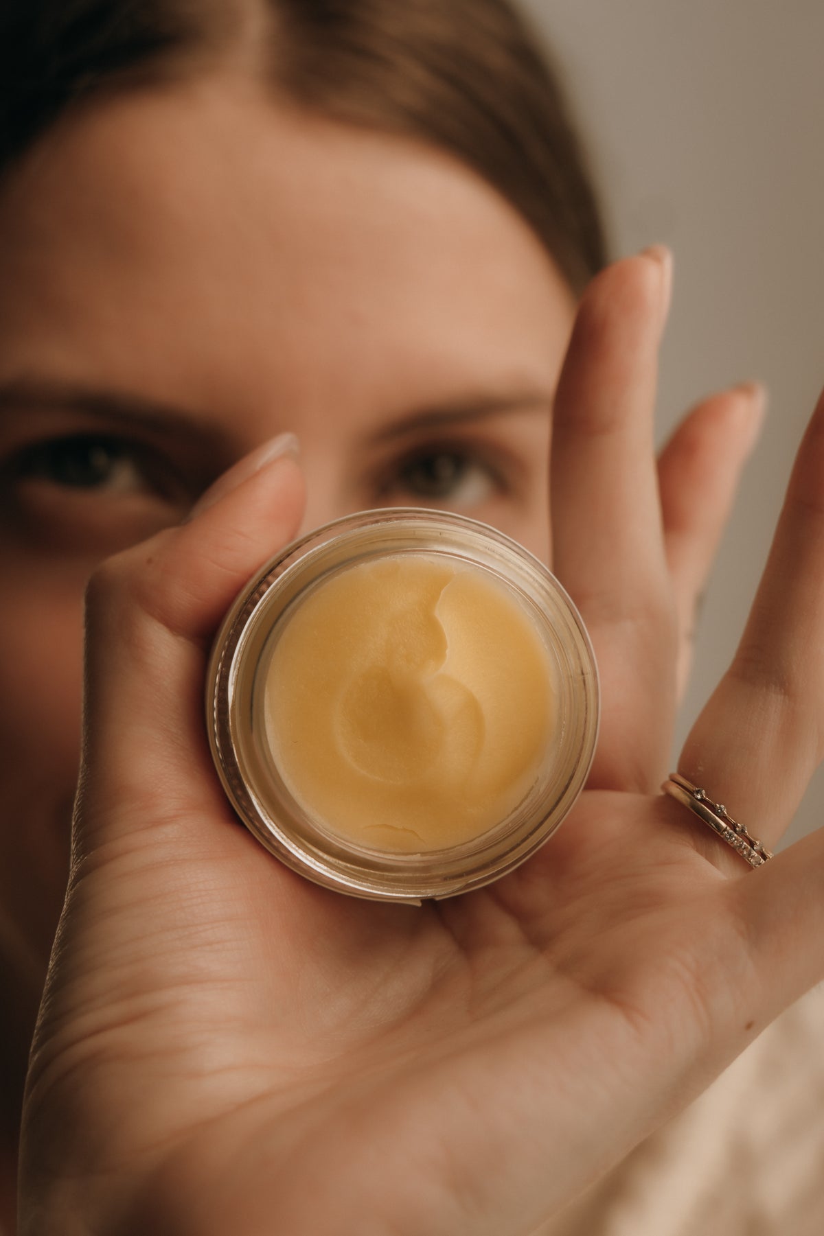 Person holding a small jar of cream close to the camera