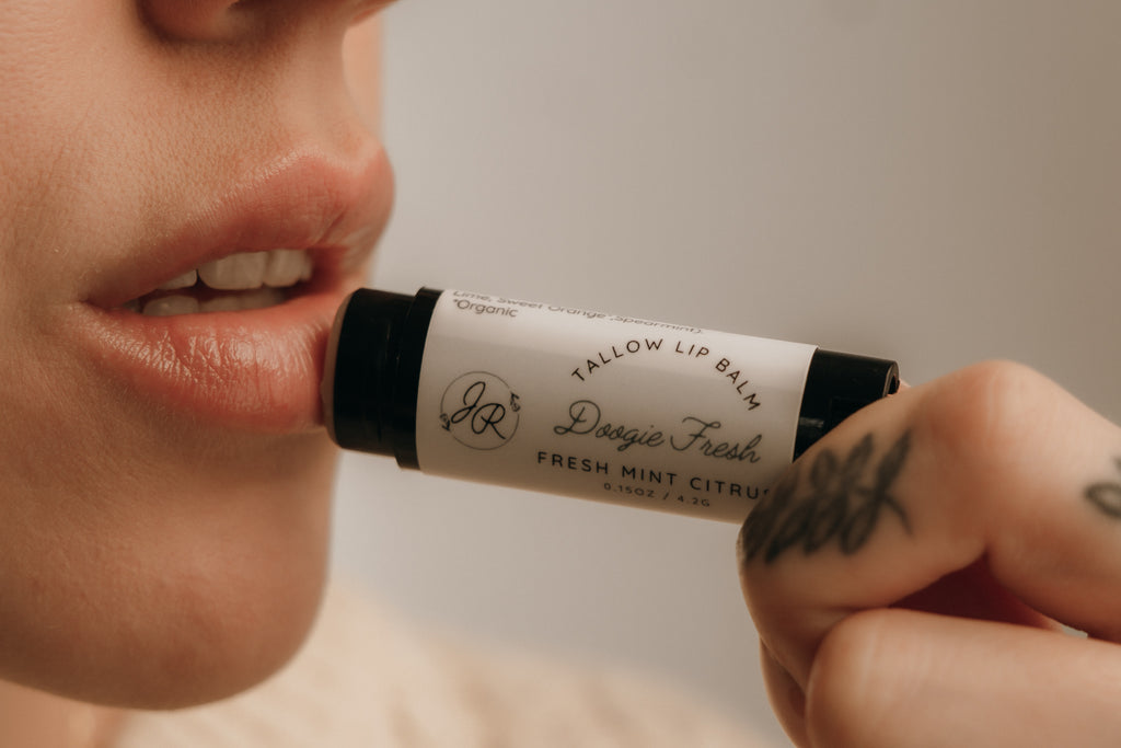 Person applying a lip balm labeled 'Fresh Mint Citrus' to their lips.