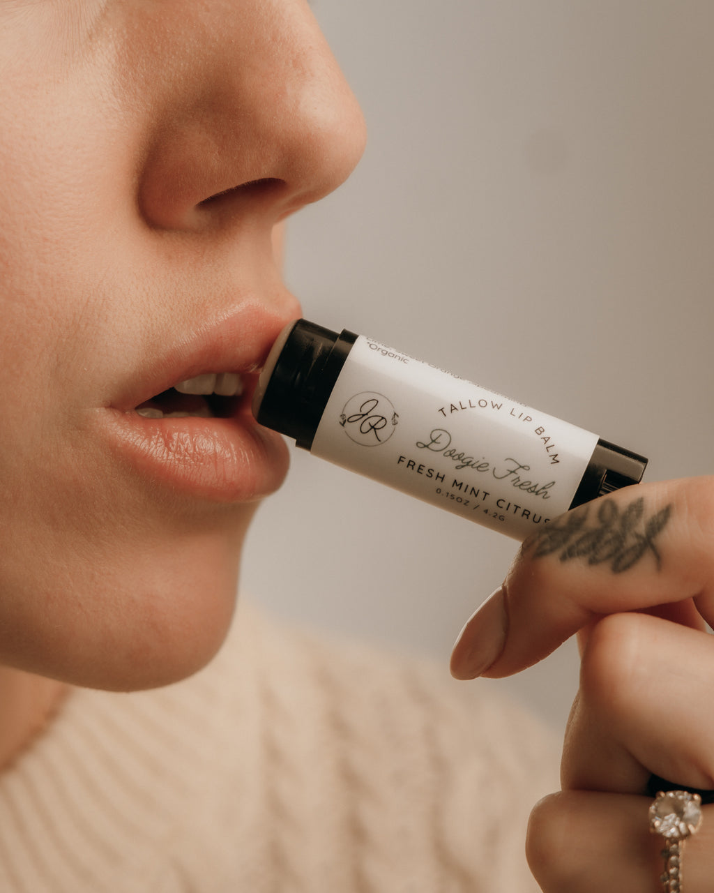 Person applying a roll-on lip balm labeled 'Fallow Lip Balm' with a neutral background.