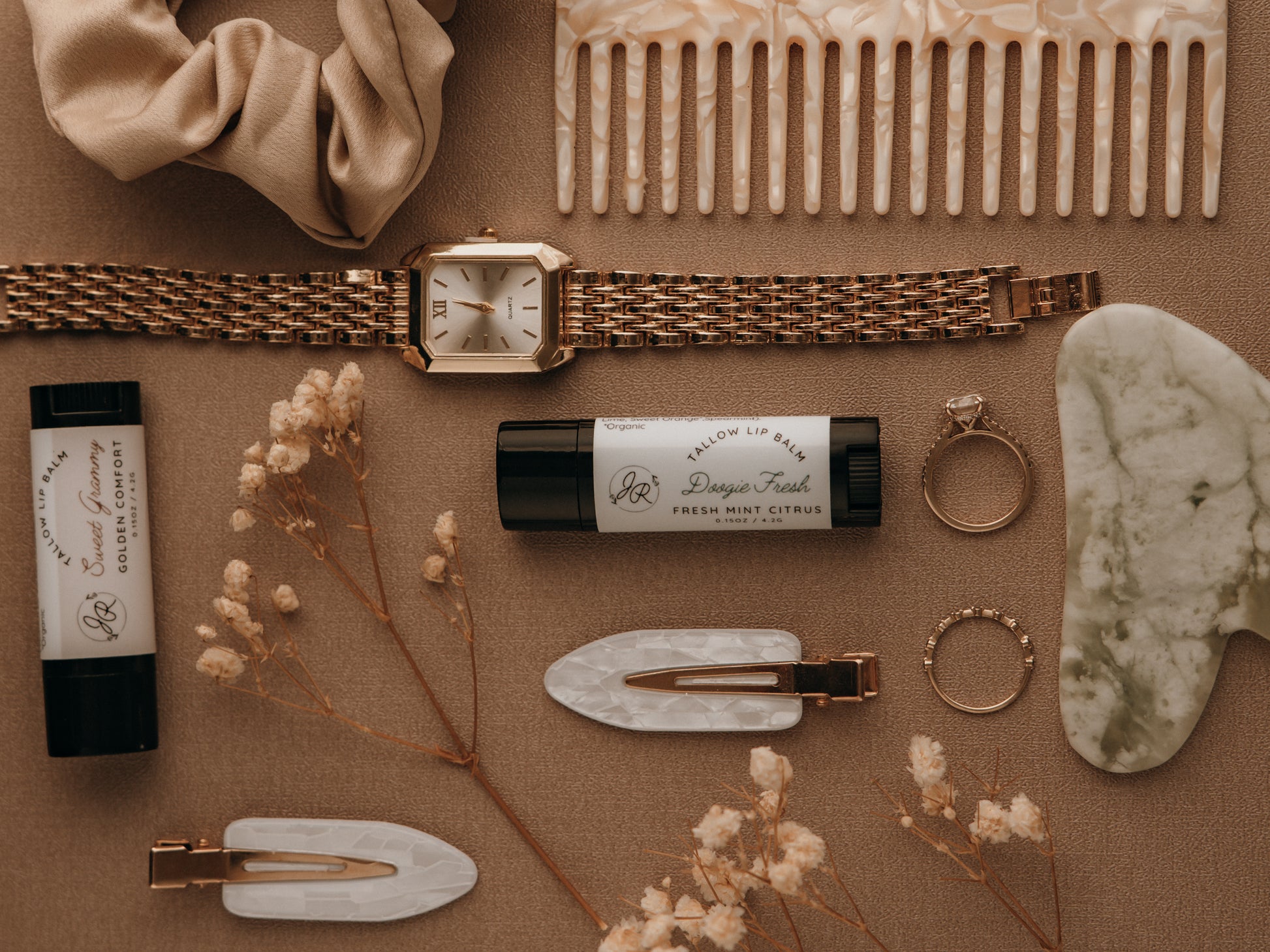 Collection of beauty and fashion items including a watch, comb, hair clips, and lip balm on a brown surface.