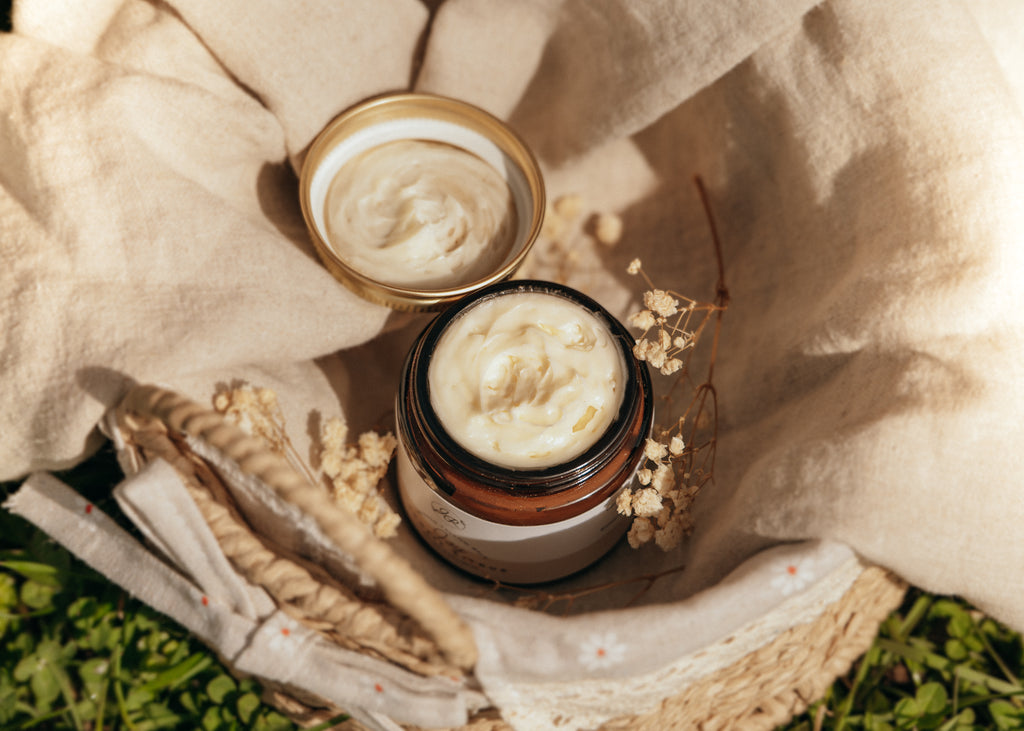 Two jars of cream on a textured surface with natural elements