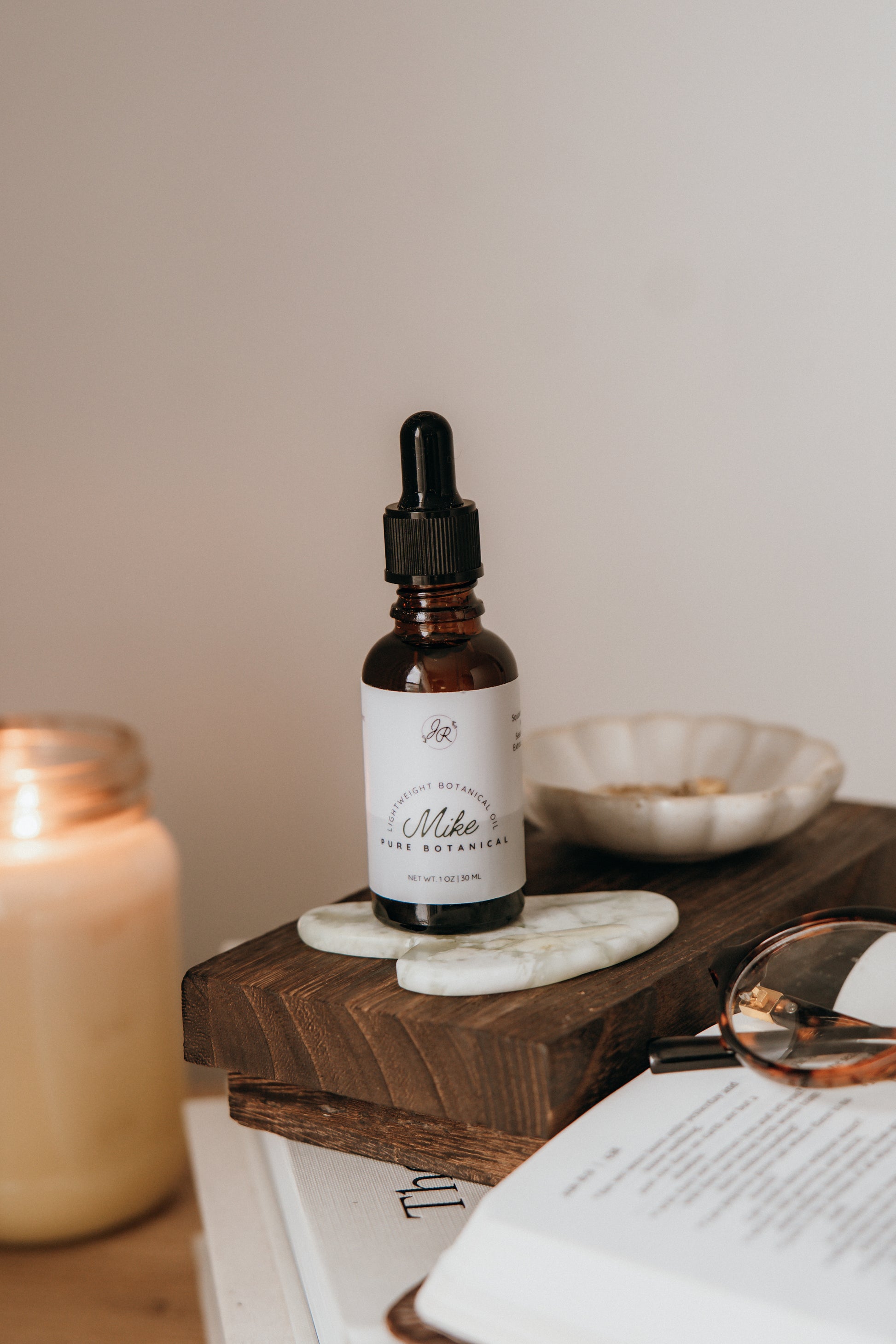 Bottle of tincture on a wooden tray with a candle and book in the background