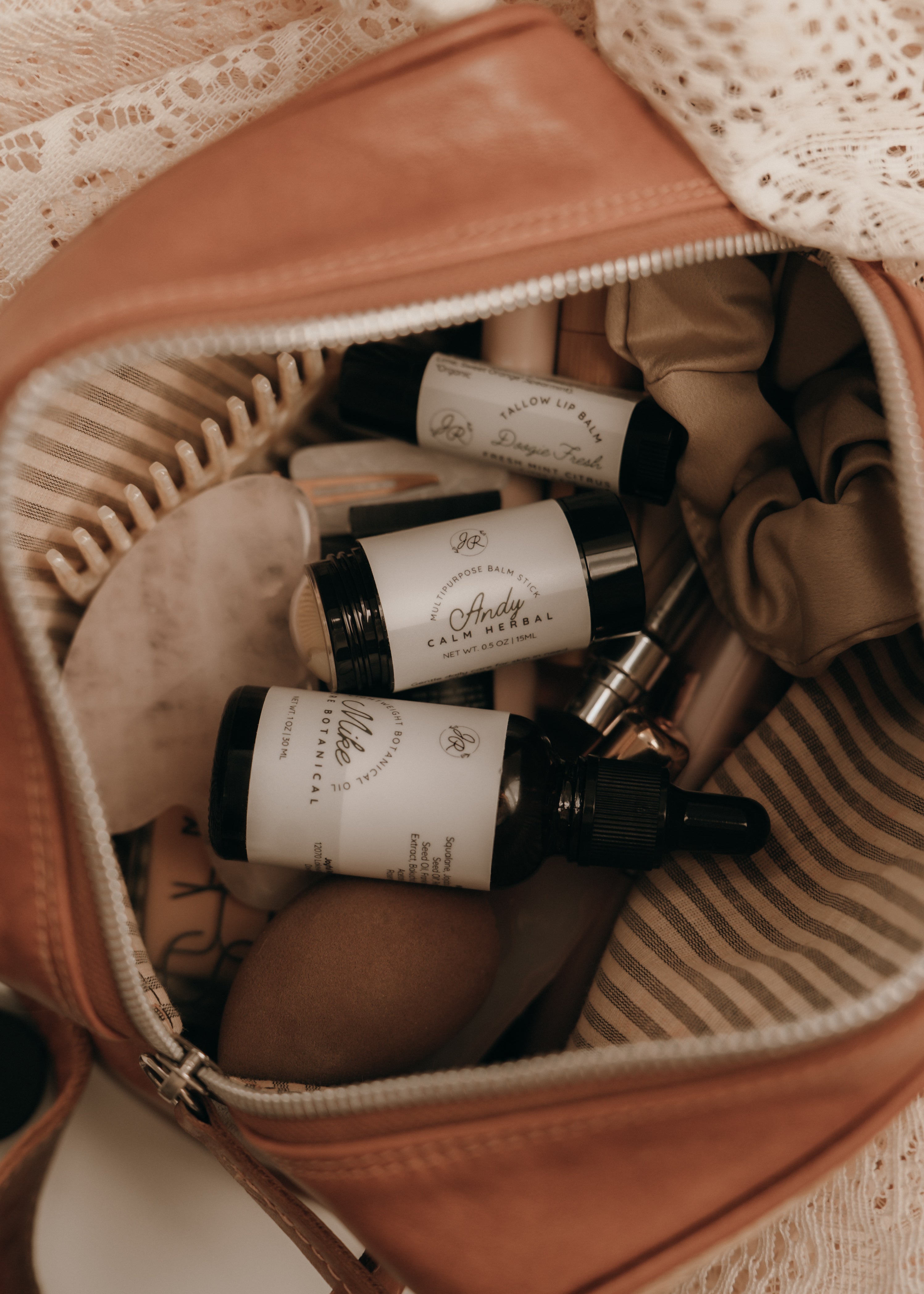 Small bottles with labels inside a brown leather bag with lace trim.