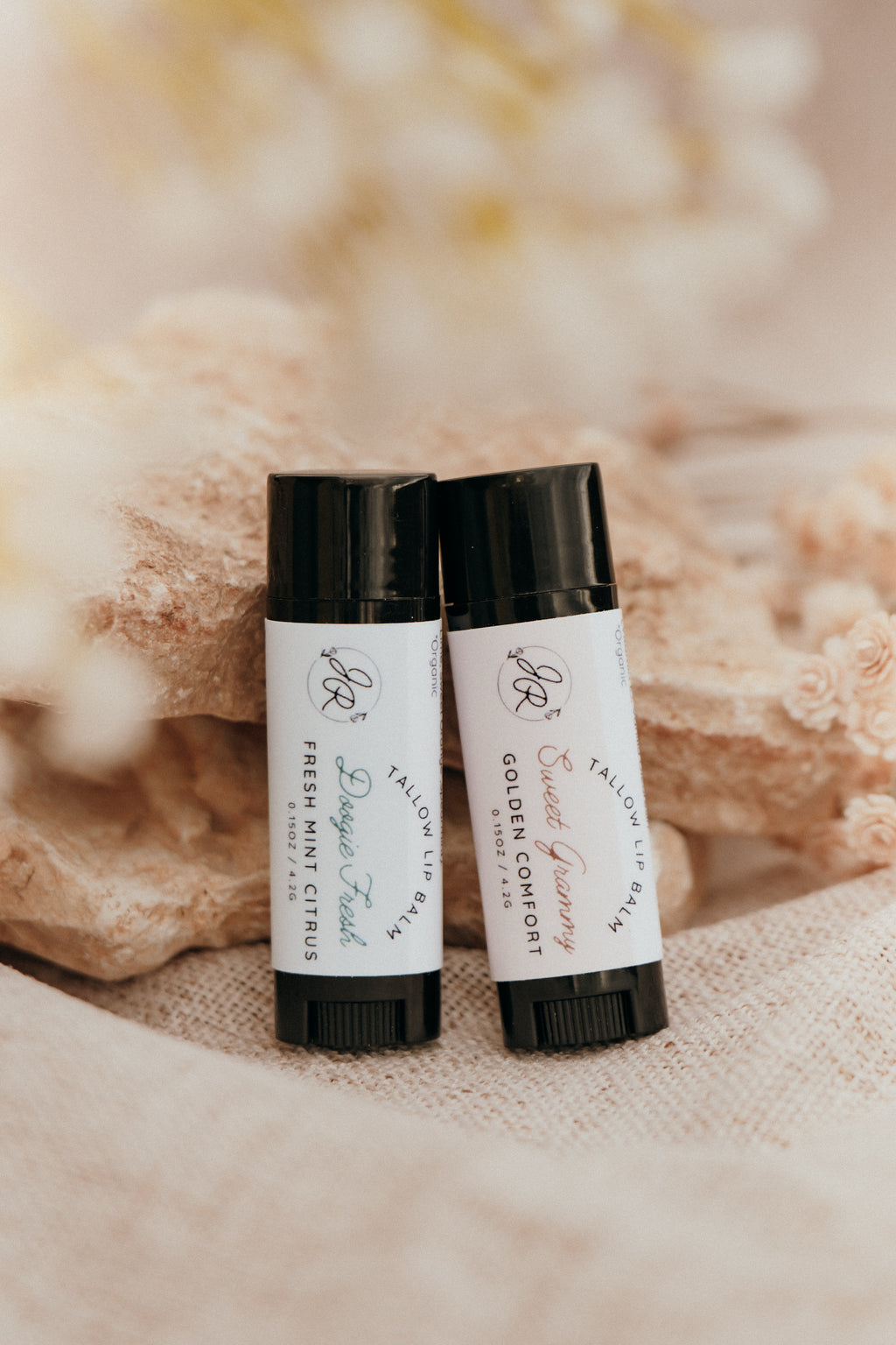 Two small bottles with black caps and white labels on a textured beige background