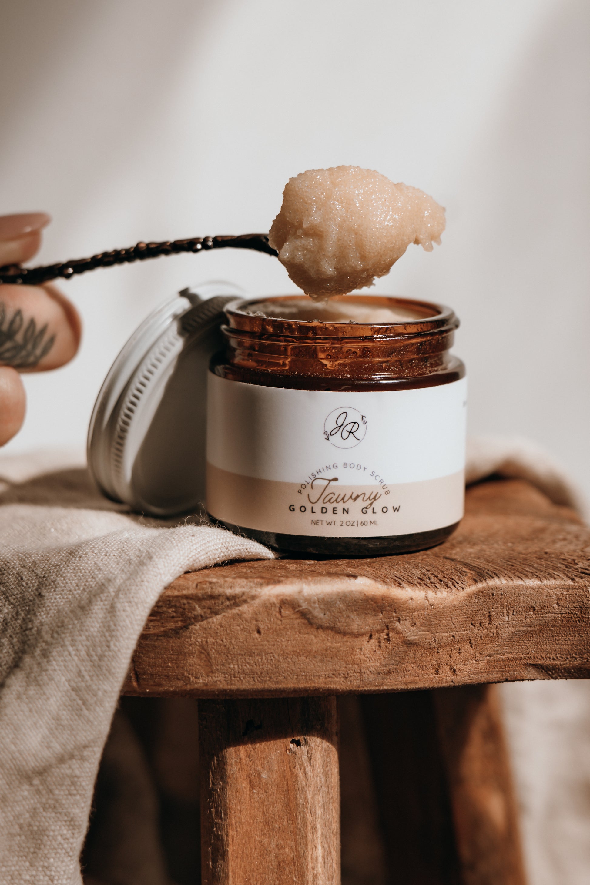 Jar of skincare product with a wooden applicator on a wooden stool.