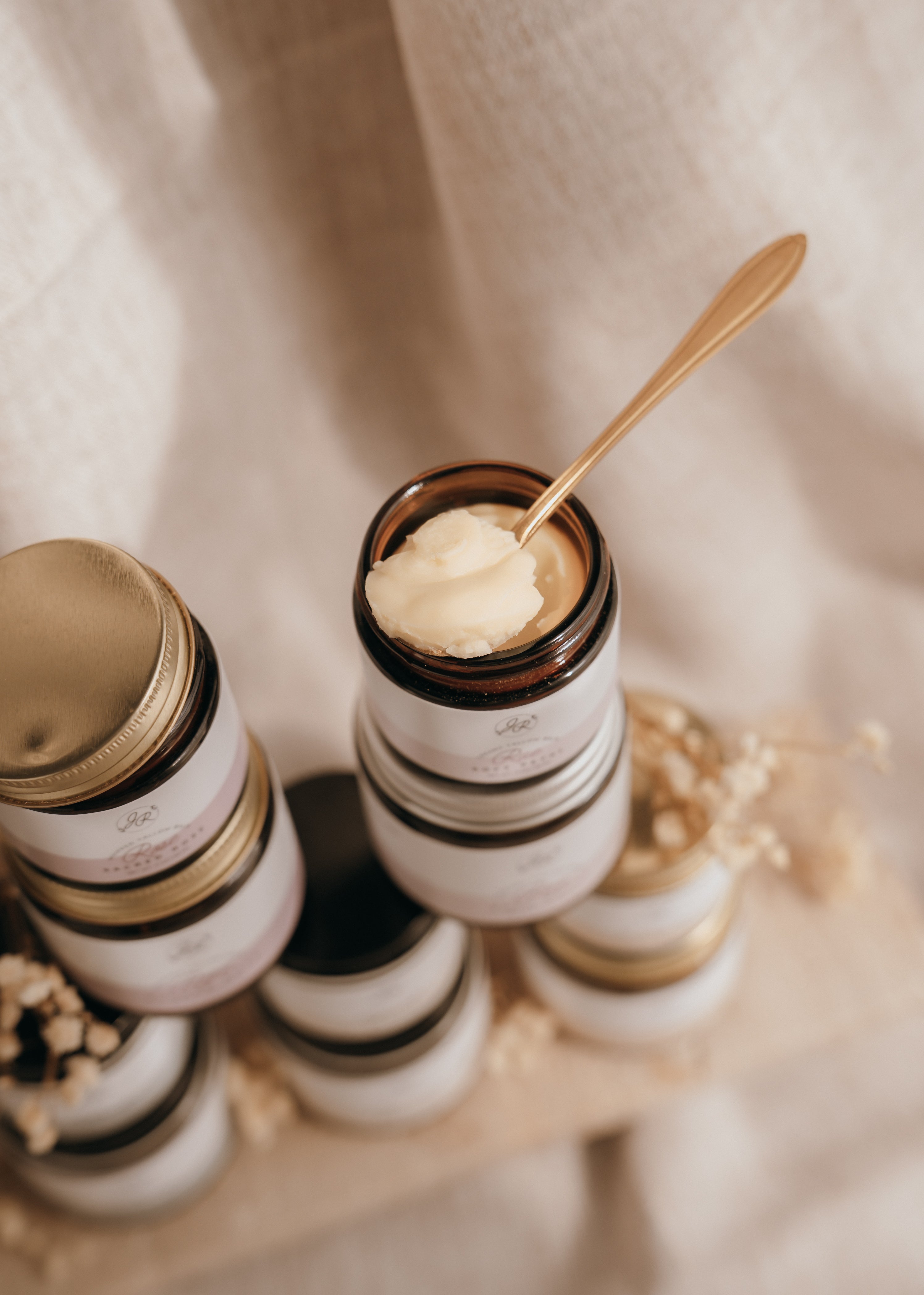 Jars of cream with a spoonful on top, set against a neutral background