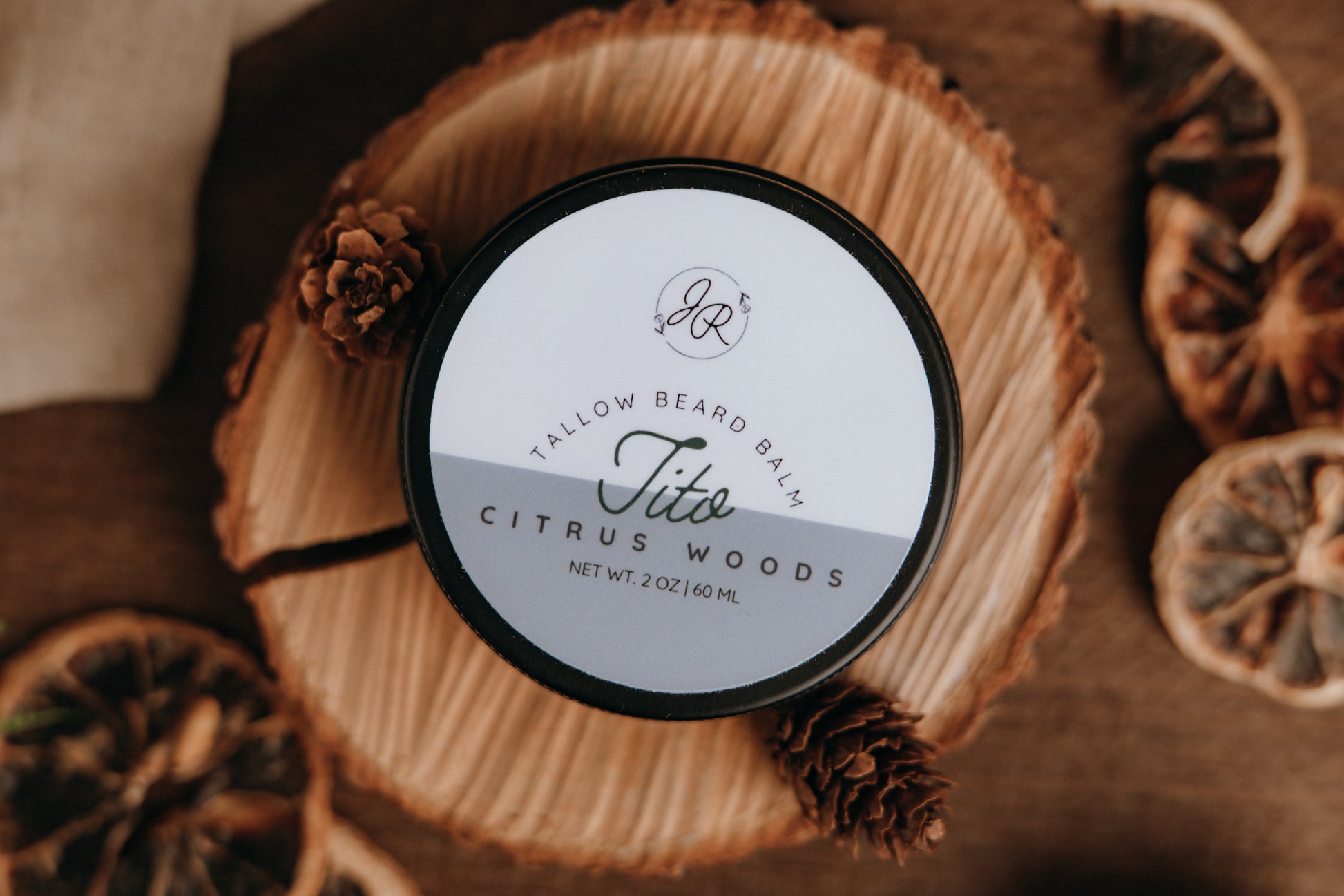 Jar of Tallow Beard Balm with Citrus Woods scent on a wooden surface with dried oranges and pine cones.